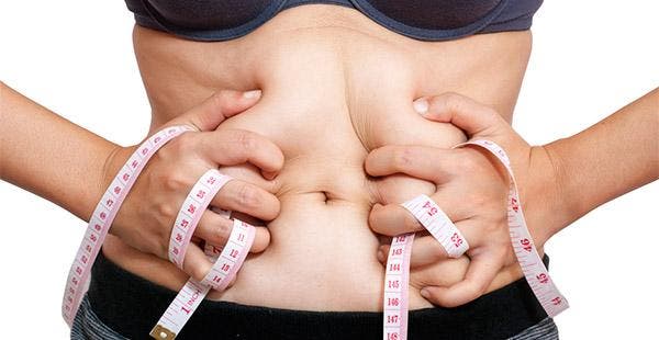 Perder barriga. Mulher mede com fita métrica a gordura abdominal 